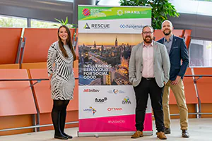 Conference Organizers enjoy a fun moment standing next to their branding.   Photo by Jeffrey Meyer.