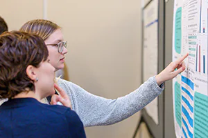 Students engage with a poster during a conference event.   Photo by Jeffrey Meyer.