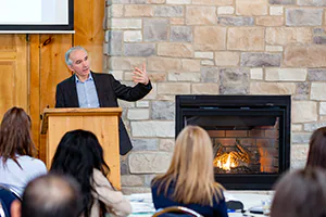 An off-site team building meeting takes place in front of a warm cabin fireplace. Photo by Jeffrey Meyer.