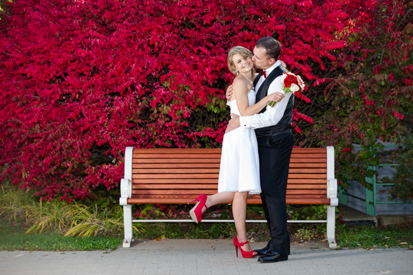Bride and groom pose next to red autumn leaves