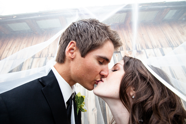 Husband and wife kiss underneath the veil